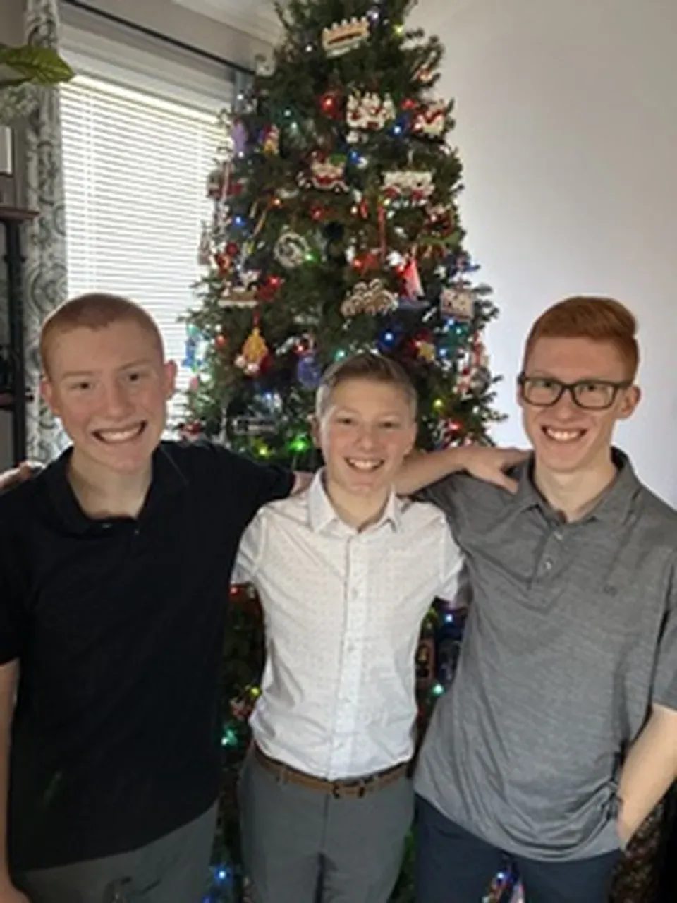 Three brothers standing before a Christmas tree